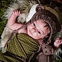 baby, infant, knitted_hat, bear_hat, crocheted_toy, teddy_bear, blanket, green_blanket, fluffy_rug, white_rug, curious, lying_down, indoor, portrait, cute, child, soft_lighting, close_up, hand, face