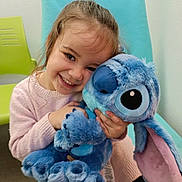 Camélia a rejoint le concours — aidez-le/la à gagner de superbes lots ! blue, blue_chair, chair, child, childhood, cuddling, cute, girl, green_chair, happy, indoor, long_hair, pink_sweater, playful, plush_toy, portrait, seated, smiling, stuffed_animal, toy