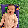 baby, smiling, infant, onesie, pillow, purple, stars, green_mat, happy, child, cute, playmat, indoors, face, portrait, young_child, lying_down, colorful, fabric, soft_toys