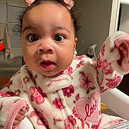 Jaylanhi joined the competition — help win amazing prizes! baby, child, face, pink_bows, floral_outfit, heart_patch, love, high_chair, fleece, indoors, curious, wide_eyes, sitting, cozy, cute, infant, person, clothing, portrait, home