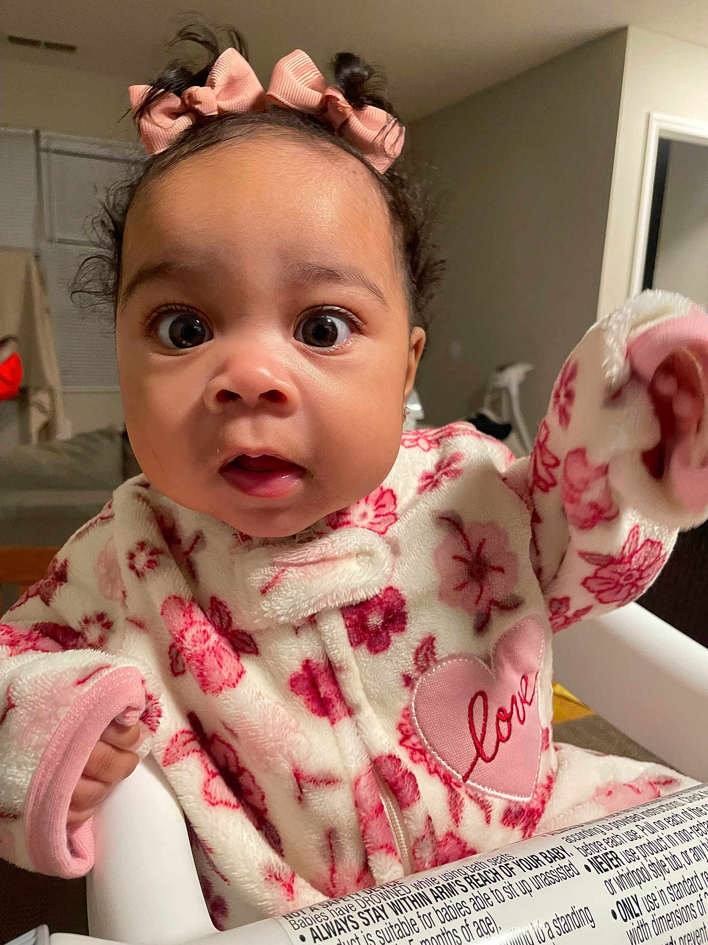 Jaylanhi joined the competition — help win amazing prizes! baby, child, face, pink_bows, floral_outfit, heart_patch, love, high_chair, fleece, indoors, curious, wide_eyes, sitting, cozy, cute, infant, person, clothing, portrait, home