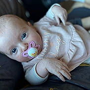 Daisy-Mae is registered to the contest to win money with this photo: baby, infant, pacifier, blue_eyes, pink_clothing, hand, face, close_up, lying_down, person, soft_focus, skin, cute, child, young, portrait, comfort, relaxing, indoor, human