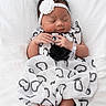 adorable, baby, child, clothing, cute, flower, hands, headband, heart_pattern, indoors, infant, lying_down, newborn, peaceful, portrait, resting, sleeping, small_feet, soft_texture, white_blanket