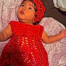 arm, baby, baby_clothing, blanket, child, crochet, curious, cute, face, hat, headwear, indoors, infant, lying_down, patterned_blanket, portrait, red_dress, skin, soft_texture, young_child