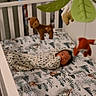 animal_toys, baby, bedroom, carpet, child, cozy, crib, decor, forest_pattern, gazing, indoor, infant, nursery, peaceful, plush_toy, sleeping_baby, soft_toys, swaddle, white_crib, woodland