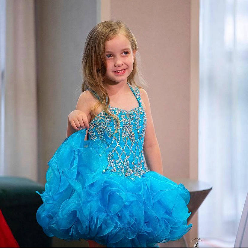 Chloé is registered to the contest to win money with this photo: aqua, blond, child_model, costume, costume_accessory, curtain, day_dress, dress, embellishment, hair_accessory, joy, one_piece_garment, person, quinceanera, ruffle, satin, teal, turquoise, window_covering, window_treatment