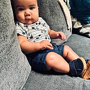 Gavin is registered to the contest to win money with this photo: baby, child, infant, couch, sofa, clothing, shorts, shirt, mickey_mouse, footwear, baby_shoes, indoor, portrait, sitting, curious, face, skin, cute, comfortable, home