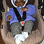 baby, car_seat, knitted_sweater, hat, booties, infant, child, seatbelt, indoor, wooden_table, curious, black_skin, face, clothing, portrait, cute, warm_clothes, hands, legs, comfort