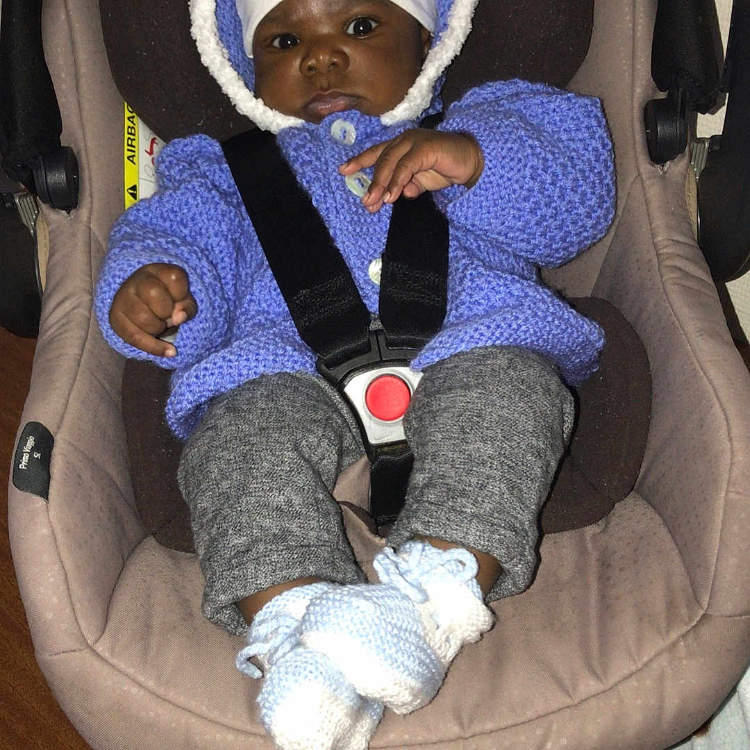 Nathael Angel a rejoint le concours — aidez-le/la à gagner de superbes lots ! baby, black_skin, booties, car_seat, child, clothing, comfort, curious, cute, face, hands, hat, indoor, infant, knitted_sweater, legs, portrait, seatbelt, warm_clothes, wooden_table