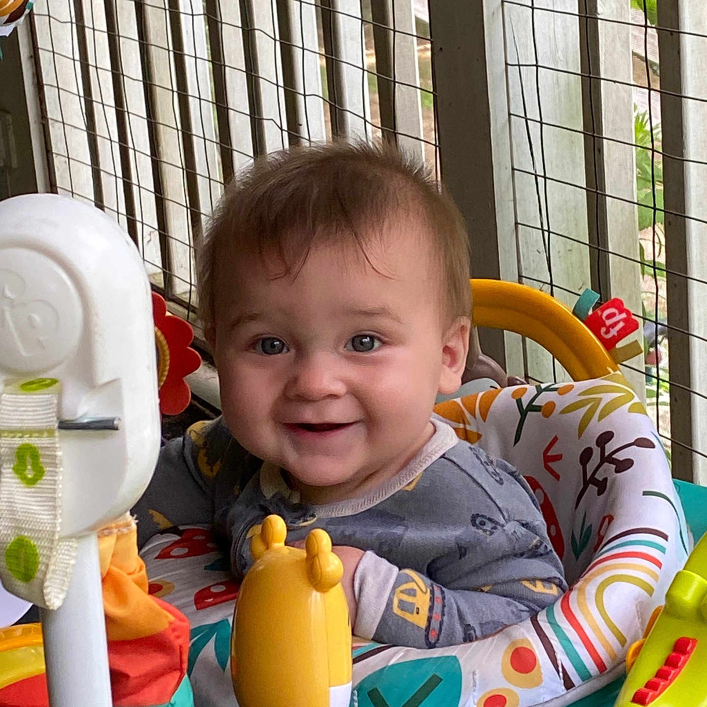 Adam is registered to the contest to win money with this photo: activity_center, baby, background, child, clothing, colorful, cute, expression, face, furniture, hair, happy, indoor, infant, pattern, person, play, seat, smiling, toy