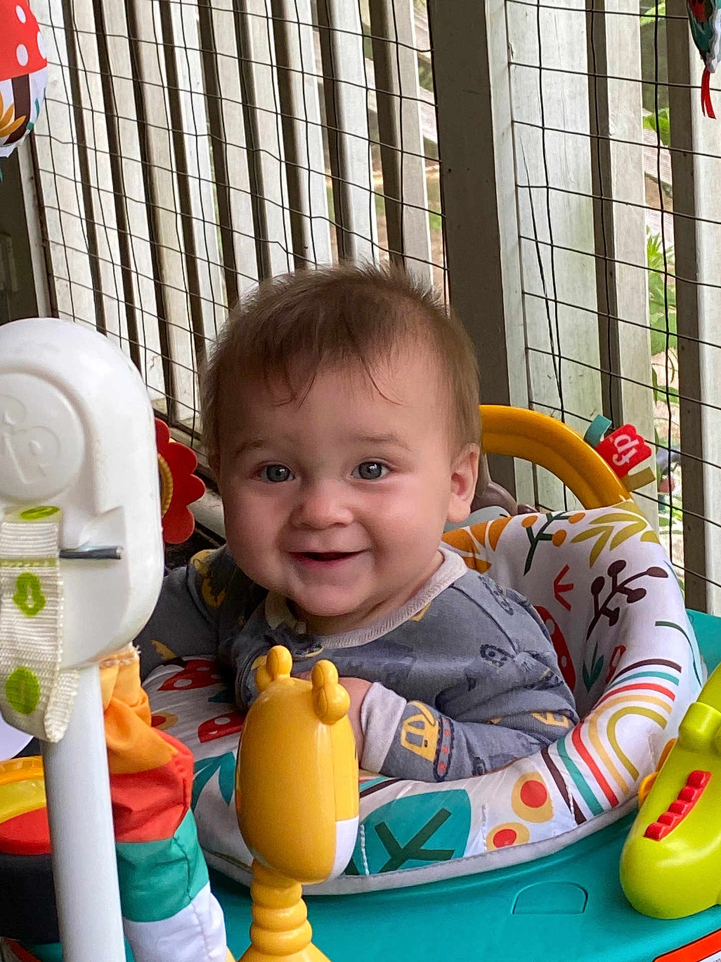 Adam is registered to the contest to win money with this photo: baby, child, smiling, face, toy, activity_center, indoor, clothing, seat, colorful, happy, expression, person, hair, furniture, play, cute, infant, pattern, background