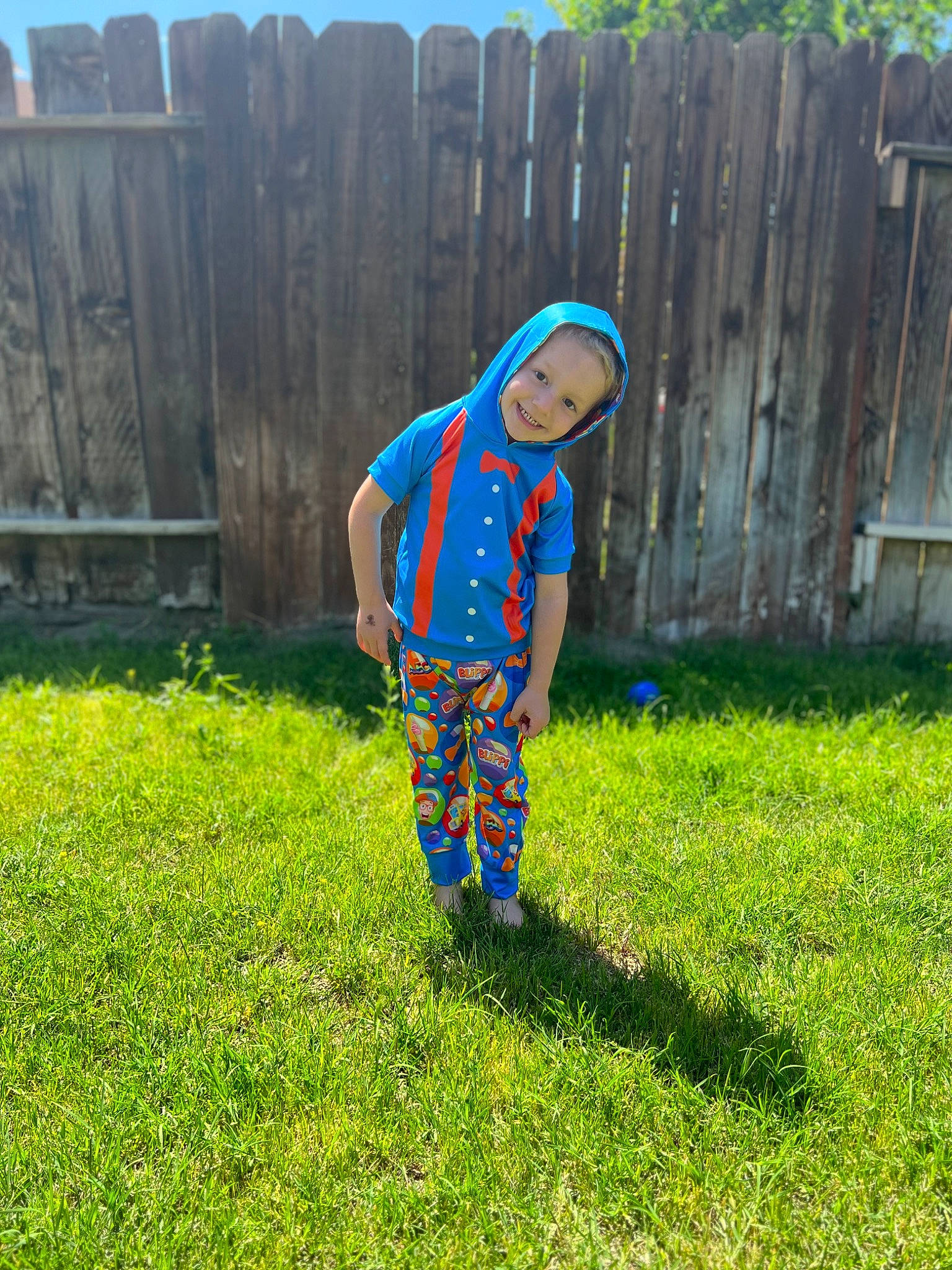 Jace is registered to the contest to win money with this photo: baby_toddler_clothing, child, electric_blue, fence, fun, garden, grass, grassland, groundcover, home_fencing, joy, lawn, leisure, pajamas, pattern, people_in_nature, person, picket_fence, sleeve, t_shirt