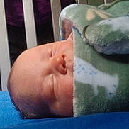 Levi is registered to the contest to win money with this photo: baby, sleeping, blanket, crib, person, blue_bed, indoors, child, face, peaceful, rest, young_child, soft, cozy, bed, home, wrapped, animal_print, blanket_pattern, infant