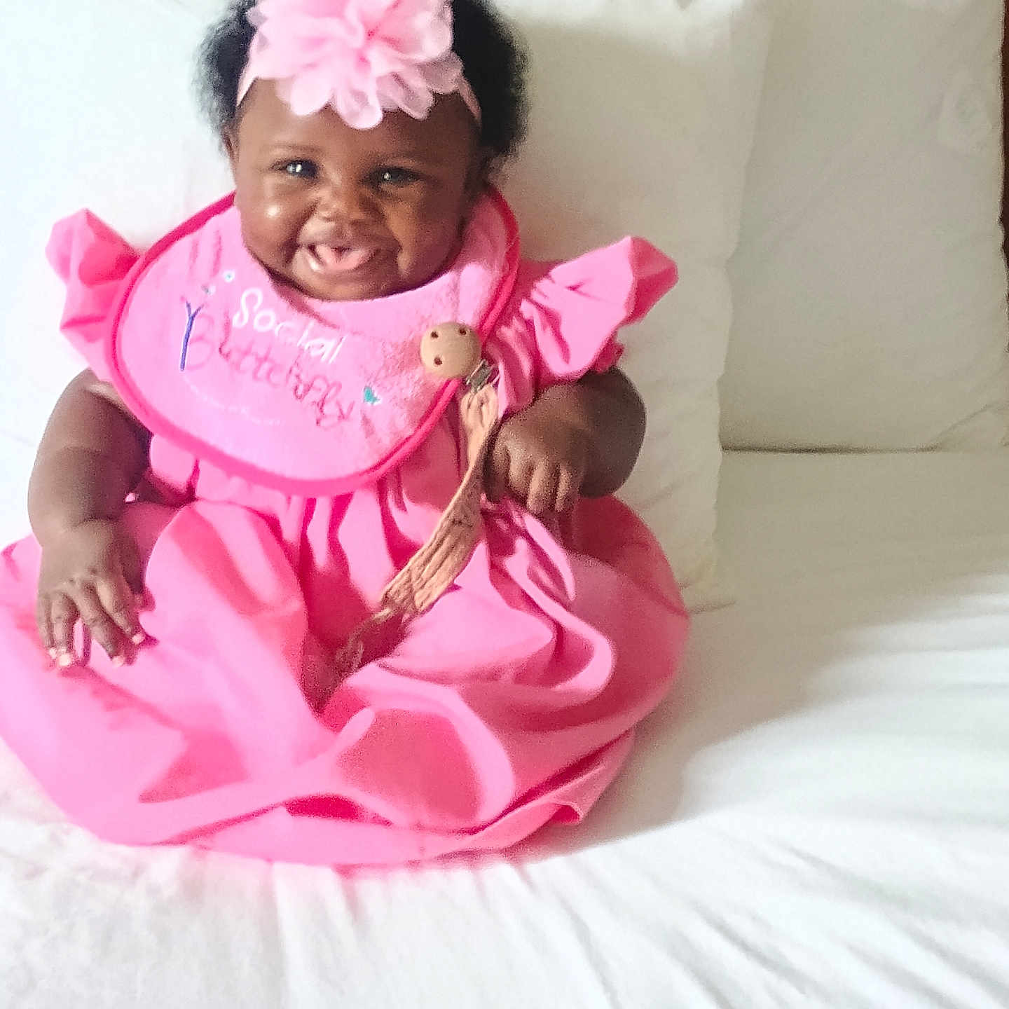 Allure joined the competition — help win amazing prizes! baby, child, infant, smiling, happy, portrait, pink_dress, flower_headband, teddy_bear, bed, pillows, bedding, indoors, sitting, dark_skin, curly_hair, facial_expression, baby_dress, celebration, cute