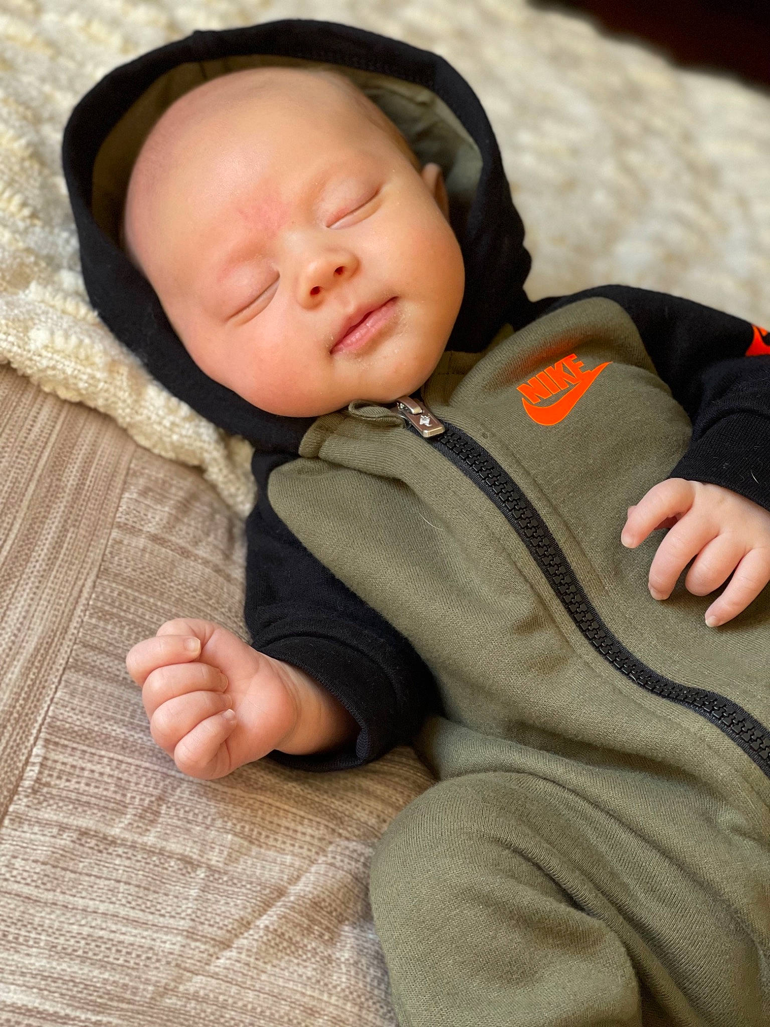 Kase is registered to the contest to win money with this photo: baby, baby_products, baby_sleeping, baby_toddler_clothing, cheek, child, collar, comfort, face, grass, knit_cap, linens, nose, person, sitting, skin, sleeve, textile, toddler, wood