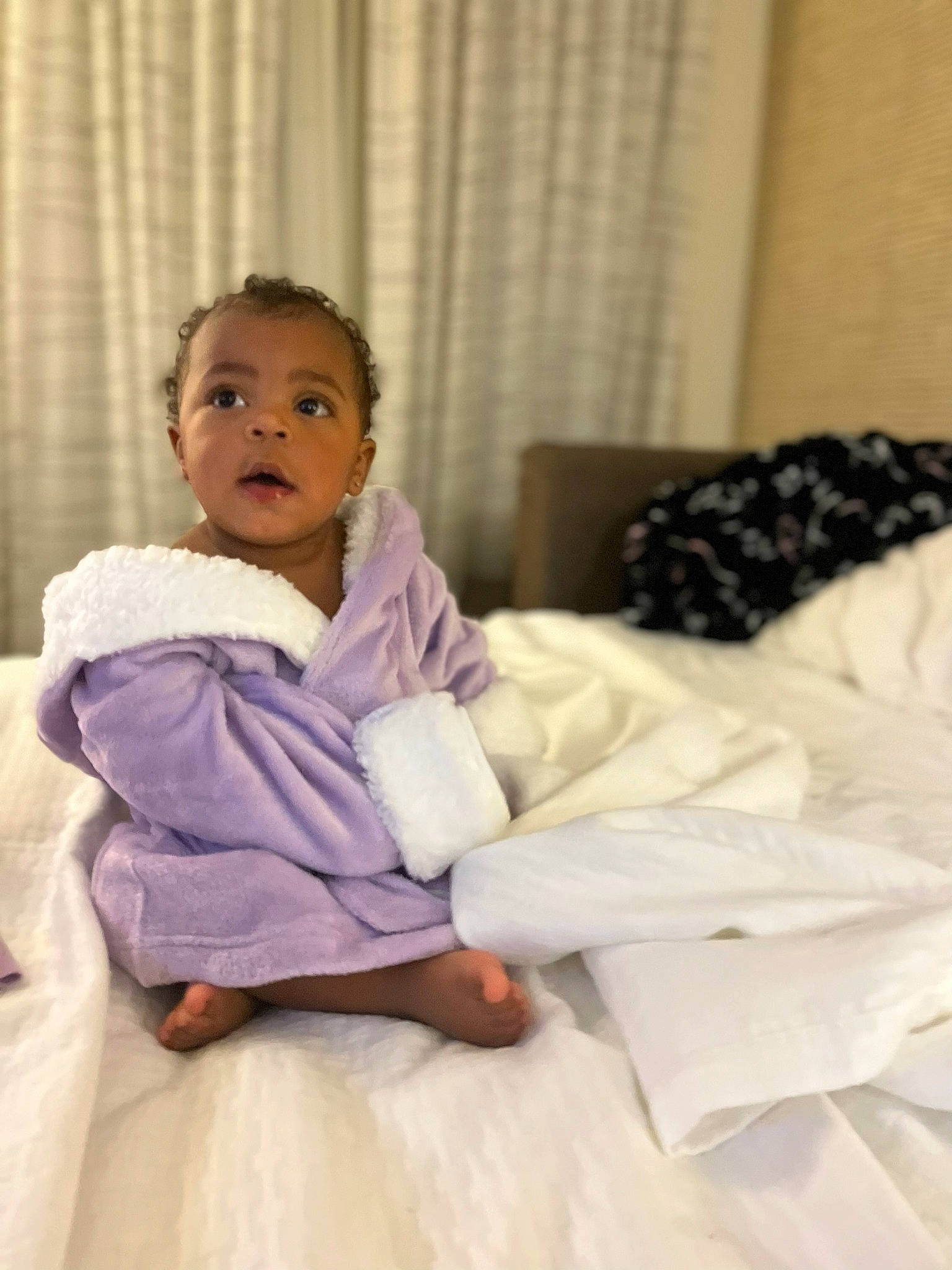 Wynter is registered to the contest to win money with this photo: baby, baby_toddler_clothing, bed, bed_sheet, bedding, blanket, child, comfort, curtain, event, fur, happy, linens, magenta, person, room, sitting, smile, toddler