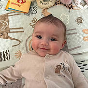 Lily joined the competition — help win amazing prizes! baby, smiling, onesie, play_mat, soft_toys, book, monkey, lion, zebra, child, cute, infant, laying_down, indoors, patterned, face, eyes, happy, cozy, apparel