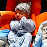 newborn, baby, sleeping, blue_pajamas, hat, orange_cushion, blanket, cozy, infant, cute, soft, resting, child, clothing, baby_seat, portrait, indoors, peaceful, tiny, warm