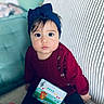 baby, big_eyes, bow, buttons, cheeks, child, couch, curious_expression, face, hair, headband, indoor, knit_sweater, musical_toy, portrait, red_sweater, sitting, striped_couch, toddler, toy_piano