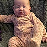 baby, infant, smiling, onesie, floral_pattern, blanket, soft_texture, comfortable, cute, child, portrait, happy, indoors, young, playful, cozy, fabric, relaxed, person, sitting