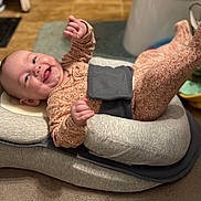 Abbi is registered to the contest to win money with this photo: baby, infant, smile, happy, pajamas, floral_pattern, cushion, lounger, indoor, carpet, floor, child, person, cute, legs_up, head_support, baby_girl, joyful, lying_down, warm_lighting