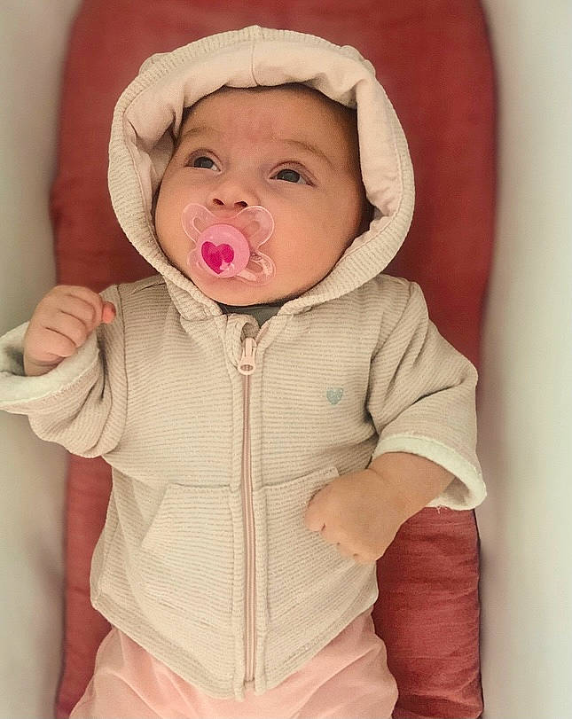 Loucia participe au concours pour gagner de l'argent avec cette photo : baby, baby_toddler_clothing, cheek, collar, comfort, eye, face, finger, gesture, happy, headwear, lip, mouth, neck, nose, organ, outerwear, person, pink, skin
