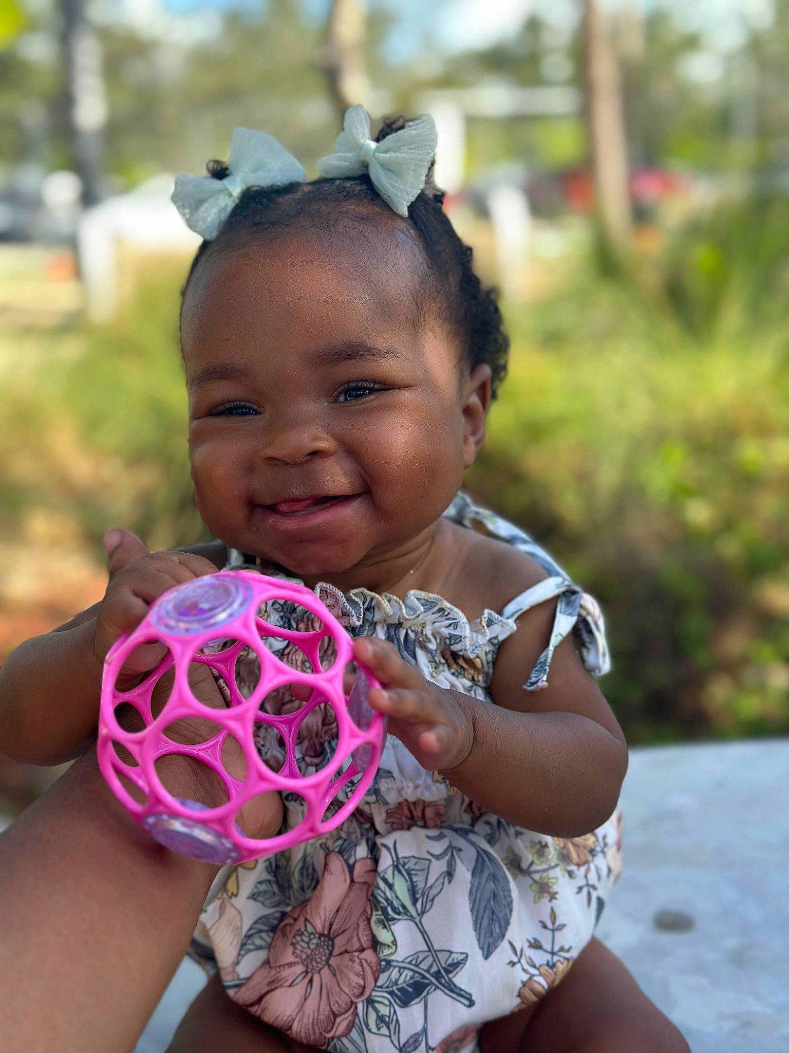 Sanai is registered to the contest to win money with this photo: baby_toddler_clothing, ball, child, face, football, fun, grass, happy, head, joy, leisure, magenta, pattern, person, personal_protective_equipment, pink, plant, recreation, smile, sports_equipment