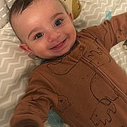 Christiano is registered to the contest to win money with this photo: baby, smiling, onesie, brown_clothing, playmat, patterned, face, infant, happy, child, cute, reaching, lying_down, indoors, person, portrait, head, closeup, baby_gesture, soft_lighting