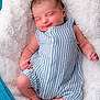 newborn, baby, infant, sleeping, smiling, striped_clothing, romper, blanket, soft_texture, cozy, cute, peaceful, portrait, human, skin, small_hands, small_feet, indoors, resting, child