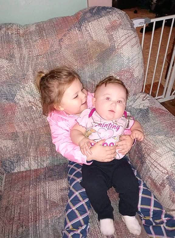 Esmae is registered to the contest to win money with this photo: baby, baby_products, baby_toddler_clothing, cheek, child, comfort, couch, eye, face, hair, happy, head, human_body, iris, lap, person, skin, sleeve, smile, toddler