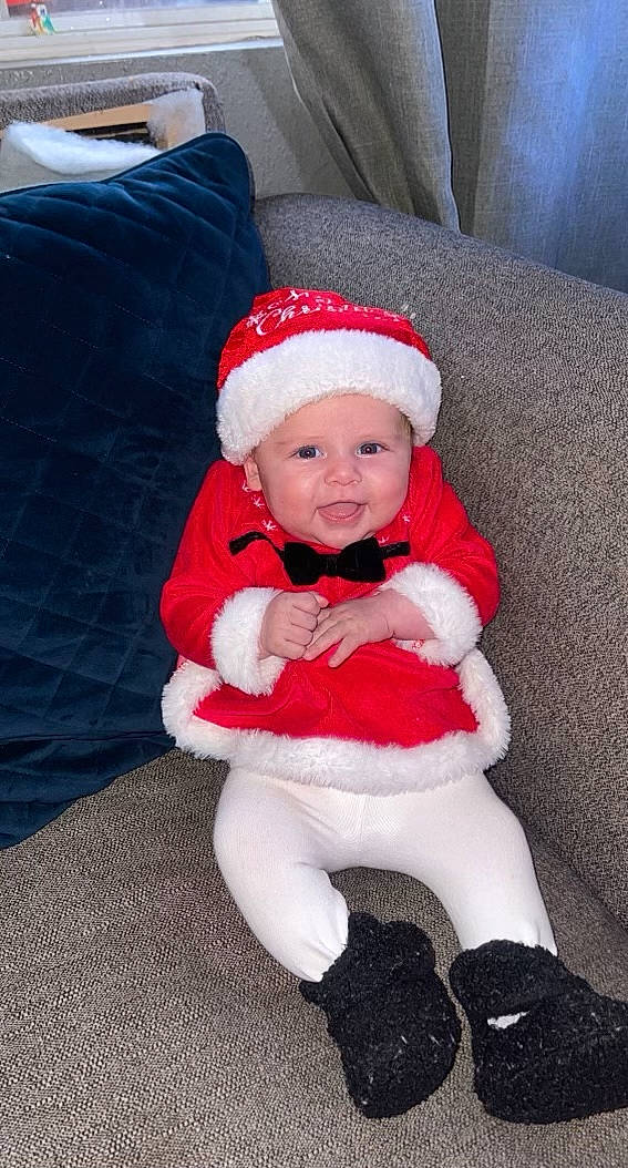 Mila joined the competition — help win amazing prizes! baby, baby_toddler_clothing, carmine, child, comfort, costume_hat, event, fictional_character, fur, fur_clothing, hat, headwear, holiday, lap, person, santa_claus, sitting, sleeve, smile, sock