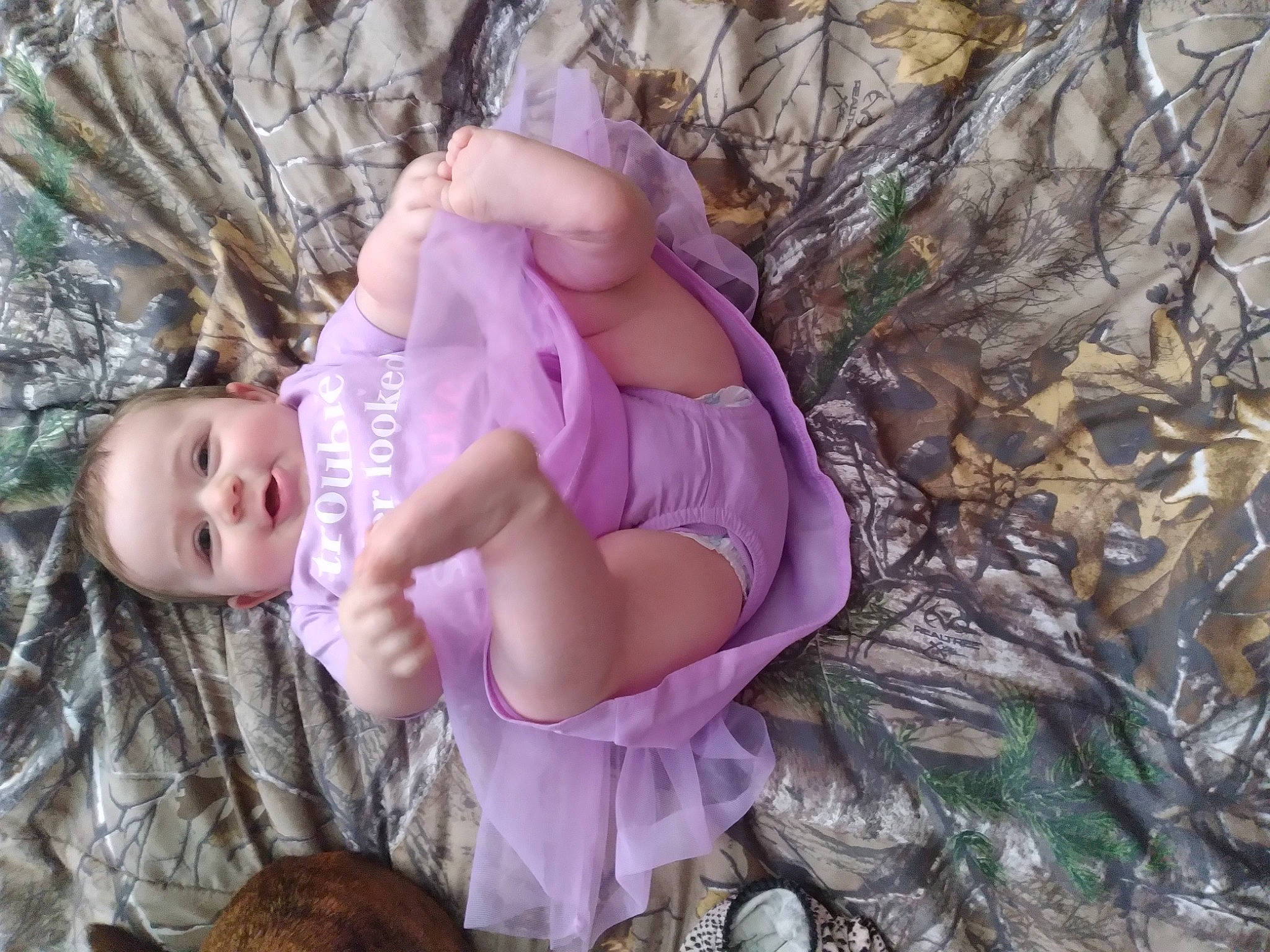 Artemis is registered to the contest to win money with this photo: baby, baby_toddler_clothing, cheek, child, doll, fashion_accessory, fawn, grass, pattern, people_in_nature, person, pink, plant, purple, sitting, skin, toddler, toy, tree, twig