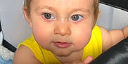 Woody is registered to the contest to win money with this photo: toddler, child, face, hand, yellow_clothing, playpen, curious, eyes, hair, indoors, baby, portrait, skin, expression, grip, soft_lighting, closeup, infant, person, young_child