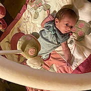 Nyla is registered to the contest to win money with this photo: baby, infant, playmat, plush_toy, animal_design, lying_down, soft_toy, child, cute, indoors, carpet, fabric, pink, gray_clothing, small_hands, head, face, newborn, play_gym, curious