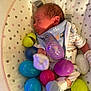 Leavon And Novael is registered to the contest to win money with this photo: newborn, baby, sleeping, plastic_eggs, easter_eggs, bib, striped_clothing, baby_seat, polka_dots, soft_lighting, infant, cozy, cute, indoors, child, resting, colorful, toy, small, peaceful