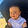 baby, child, stroller, outdoor, sunlight, face, smile, clothing, seatbelt, person, infant, head, cute, portrait, young_child, baby_clothes, happy, daylight, rest, baby_stroller