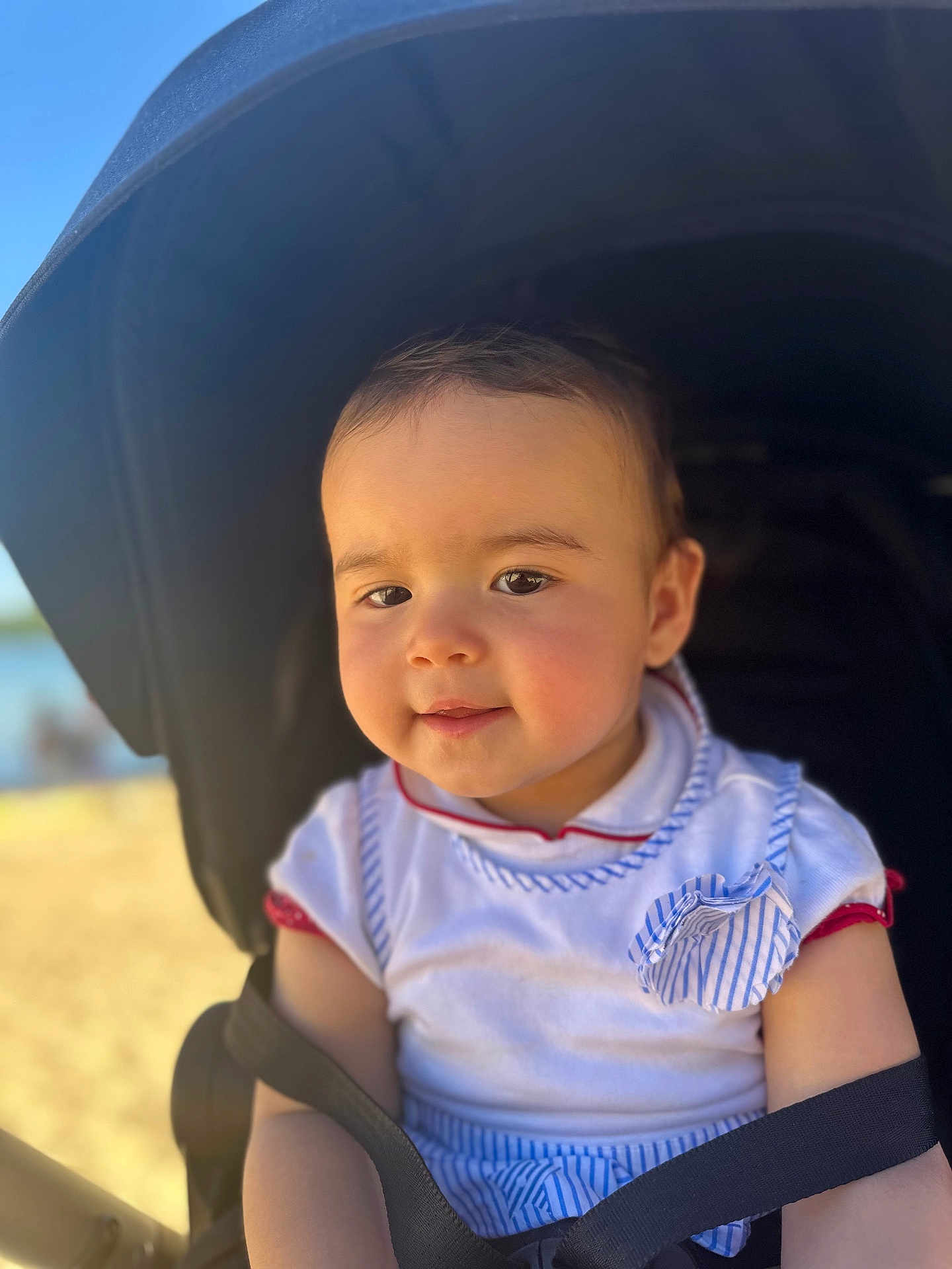 Celia a rejoint le concours — aidez-le/la à gagner de superbes lots ! baby, child, stroller, outdoor, sunlight, face, smile, clothing, seatbelt, person, infant, head, cute, portrait, young_child, baby_clothes, happy, daylight, rest, baby_stroller