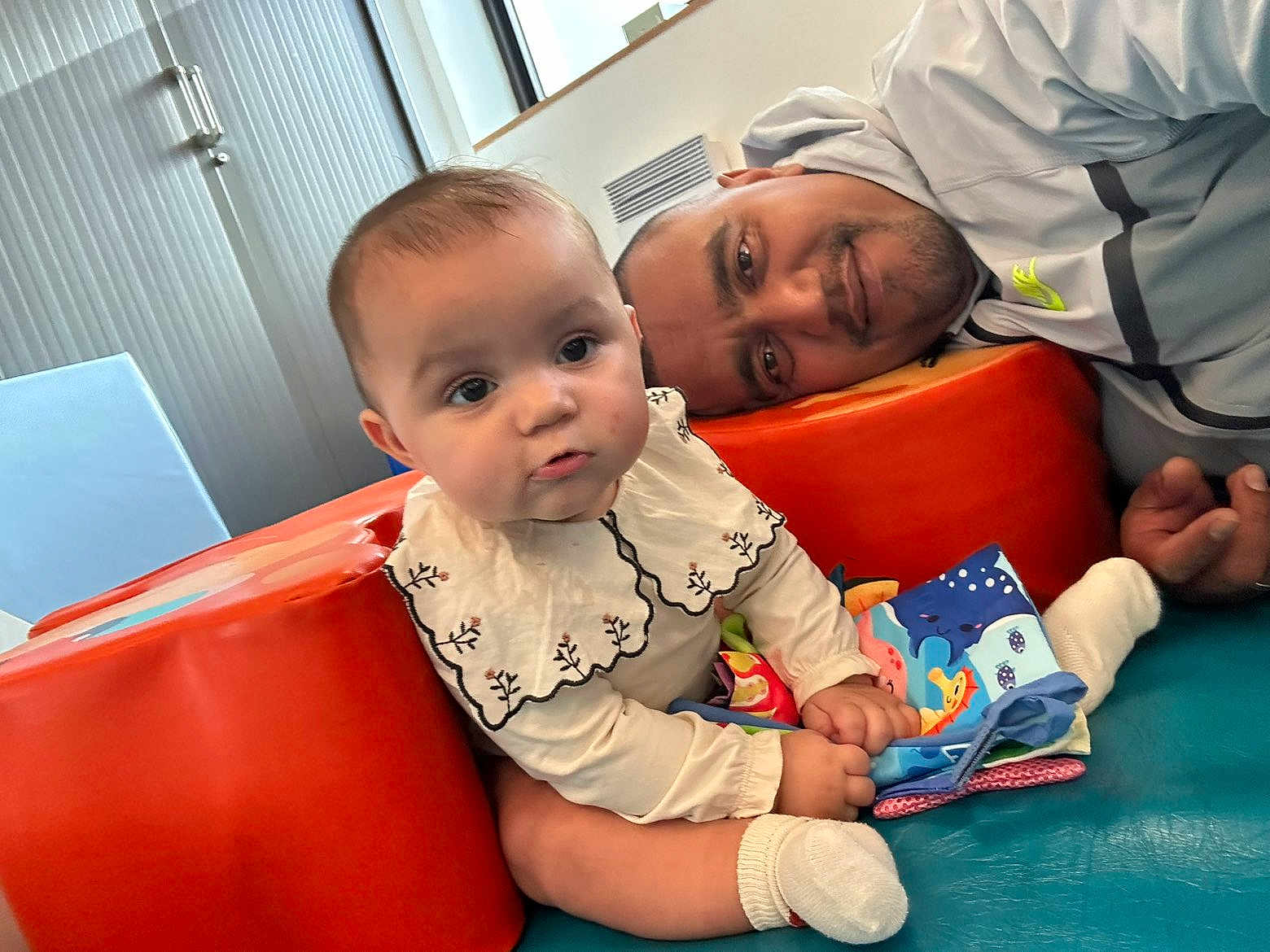 Manoune participe au concours pour gagner de l'argent avec cette photo : adult, baby, bonding, book, child, closeup, clothing, colorful, curious, face, family, happy, indoor, padded_surface, person, playtime, sitting, smiling, sock, toy