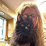 black_cat, cabinet, casual, cat, eyes, face, fur, glasses, hand, holding, home, indoor, kitchen, light, long_hair, person, pet, whiskers, window, woman