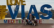 Devine a rejoint le concours — aidez-le/la à gagner de superbes lots ! boardwalk, casual_clothing, cloudy_sky, colorful, crouching, daytime, dog, fence, happy, leisure, letters, outdoor, person, pet, playful, scenic, sign, smiling, tourist_spot, two_dogs