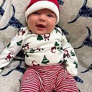 Adalynn is registered to the contest to win money with this photo: baby, infant, smiling, christmas, holiday, pajamas, hat, santa_hat, red, white, striped_pants, blanket, pattern, face, happy, cute, lying_down, cozy, festive, child