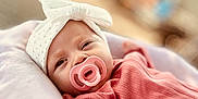 Hazel joined the competition — help win amazing prizes! baby, infant, pacifier, headband, bow, pink_clothing, cute, face, portrait, closeup, soft_focus, indoors, cushion, resting, newborn, child, sleepy, adorable, warm, cozy
