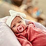 baby, infant, pacifier, headband, bow, pink_clothing, cute, face, portrait, closeup, soft_focus, indoors, cushion, resting, newborn, child, sleepy, adorable, warm, cozy