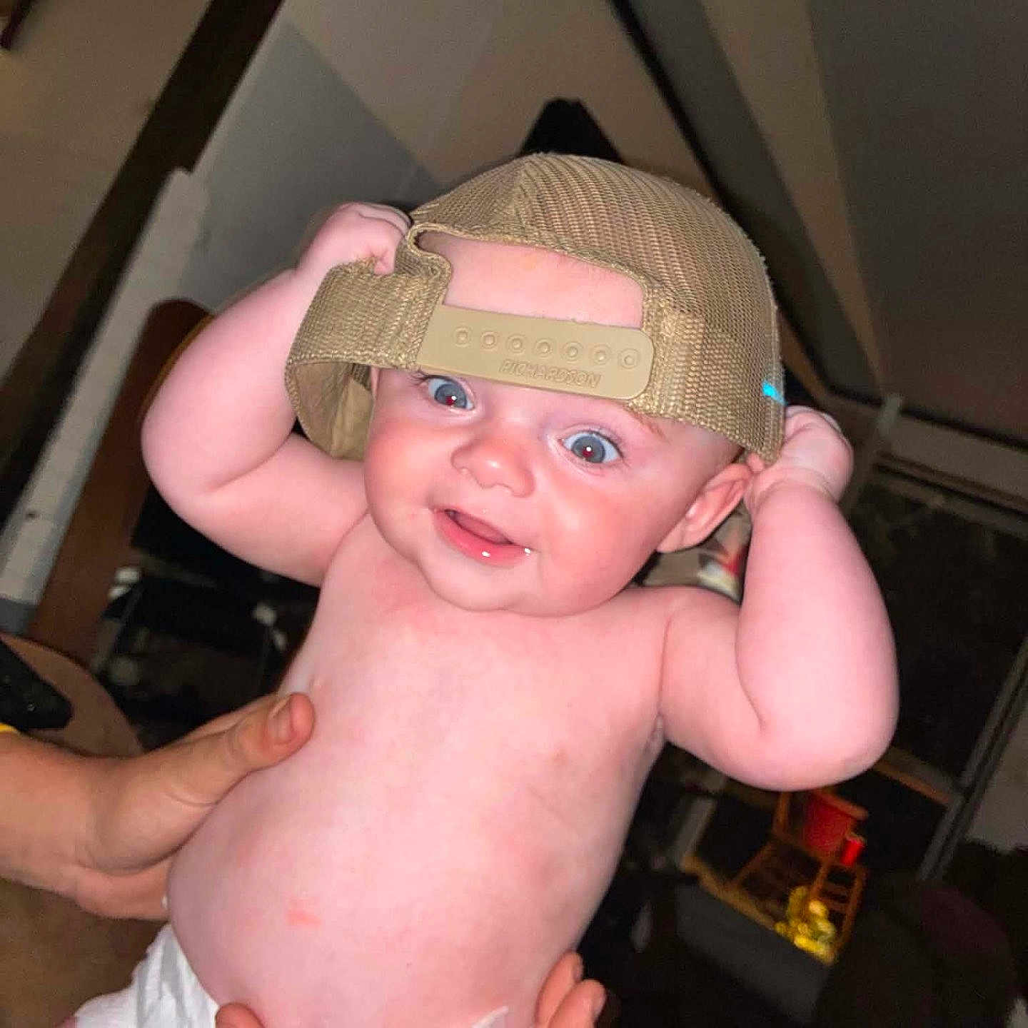 Colson joined the competition — help win amazing prizes! baby, infant, cap, hat, diaper, hands, indoor, smile, cheeks, blue_eyes, person, cute, child, holding, expression, headwear, skin, playful, room, portrait