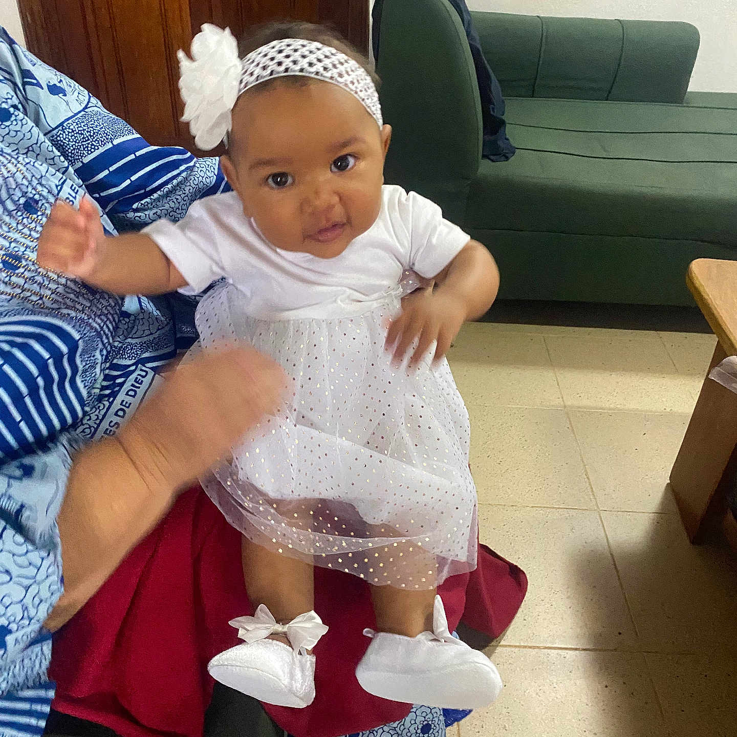 Athalia participe au concours pour gagner de l'argent avec cette photo : adult, baby, child, couch, curious, cute, door, floor, flower, footwear, hand, headband, home, indoor, infant, patterned_clothing, person, seated, sofa, white_dress