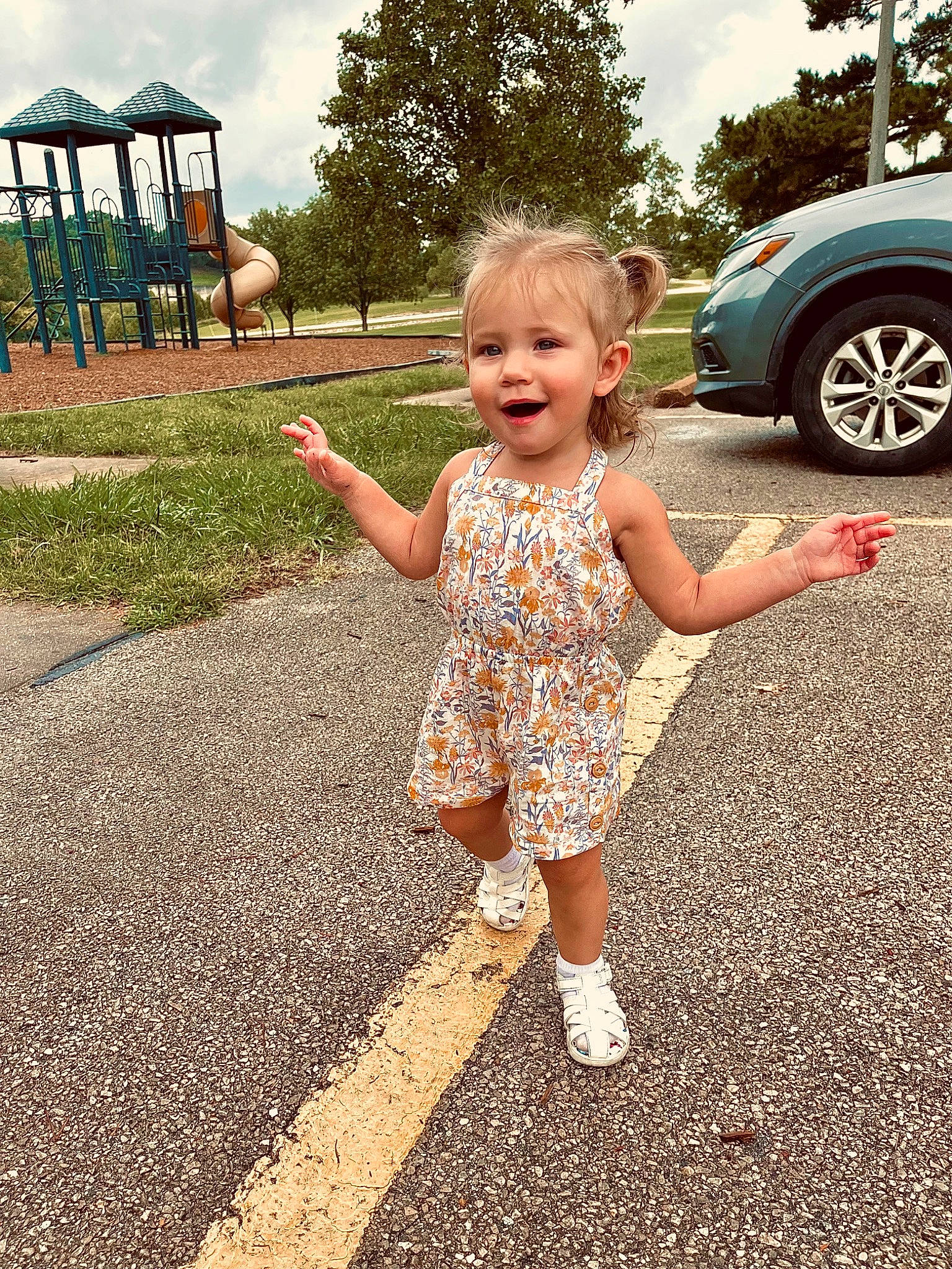Aubrey is registered to the contest to win money with this photo: asphalt, car, cloud, fun, gesture, grass, happy, joy, land_vehicle, leisure, people_in_nature, person, recreation, road, sky, smile, summer, tire, toddler, tree