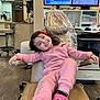child, girl, smile, pink_clothing, pink_shoes, dental_chair, office, computer_monitors, desk, flooring, happy, hair_accessory, indoor, person, furniture, waiting_room, medical_office, relaxed, casual, healthcare