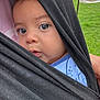 baby, child, face, eyes, black_cloth, wrap, outdoor, grass, park, person, infant, closeup, portrait, curious, head, skin, blue_clothing, hand, daylight, nature