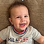 baby, child, smiling, happy, couch, cushion, clothing, toddler, face, person, indoor, portrait, sitting, cute, hair, apparel, pattern, fabric, relaxing, casual