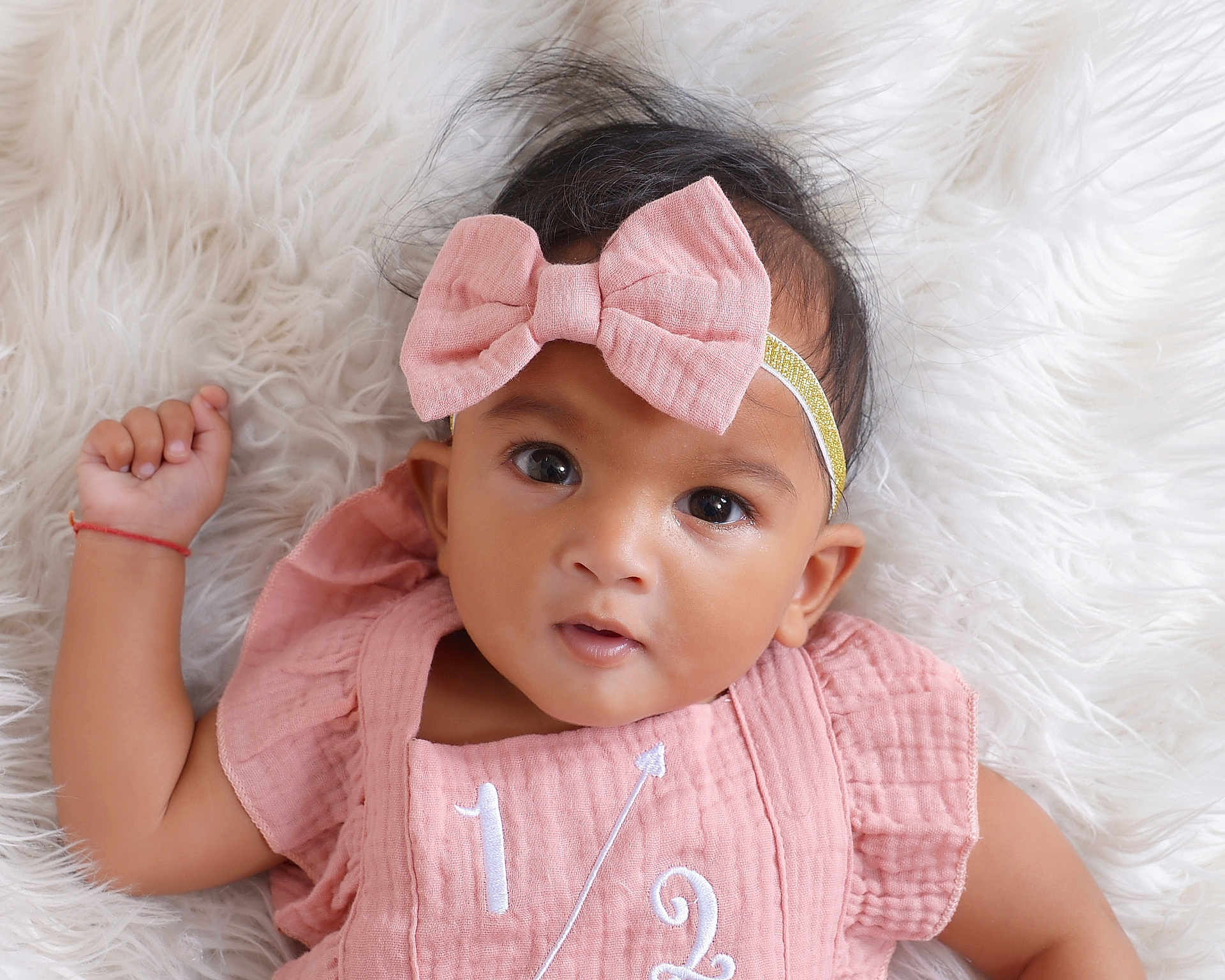 Dixie joined the competition — help win amazing prizes! baby, child, infant, headband, pink_bow, pink_outfit, lying_down, fluffy_background, curious_expression, close_up, portrait, soft_texture, cute, adorable, young_child, indoor, person, face, eyes, hand